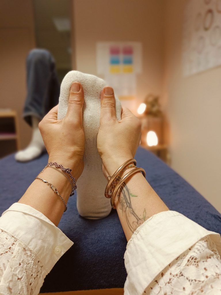 Réflexologie plantaire Une personne masse une plante de pied sur une table de soin dans un cadre relaxant.